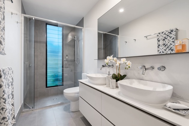 Sleek white double vanity with large mirror in a modern bathroom renovation